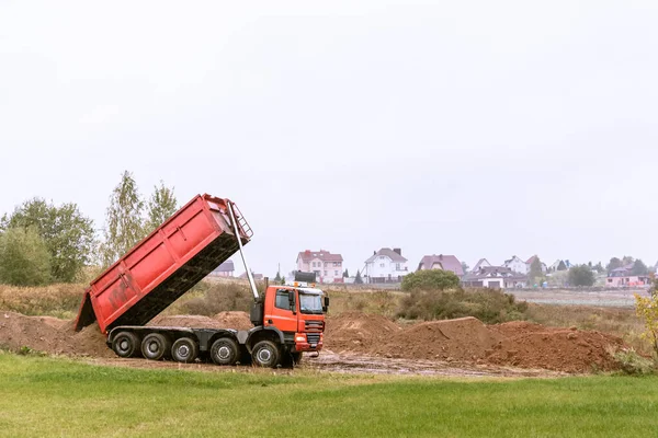 Un gran camión volquete de 70 toneladas trajo arena a un nuevo sitio de construcción para agregar tierra —  Fotos de Stock