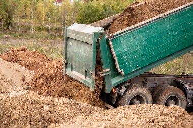A large 70-ton dump truck brought sand to a new construction site to add land