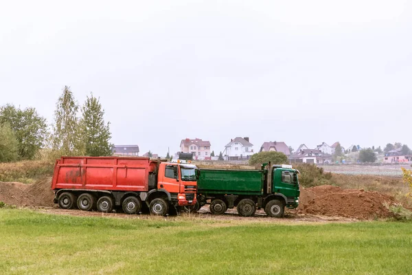 Dos grandes camiones volquete de 70 toneladas trajeron arena al sitio para agregar al nuevo sitio de construcción —  Fotos de Stock