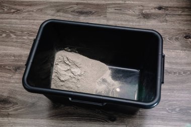 Fayans döşemede kullanılmak üzere çimento karışımı hazırlama. İçinde su ve çimento bulunan gevşek bir süpürme kabı. İnşaat süreci, dekorasyonun aşamalarından biri. Yakın plan..