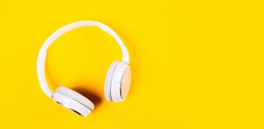 Sarı arka planda beyaz kulaklıklar. Müziğin üst görüntüsü. Etrafı sessiz, içi gürültülü. Yabancı sınırlara saygı. Ufuk pankartı.