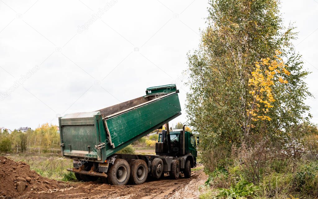 A large green 70-ton dump truck brought sand to a new construction site to add land
