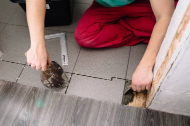 Kiremit döşemek için bir adam spatula ile çimento koyar. Bitirmek bir apartman dairesini onarmanın aşamalarından biridir. İşlem sırasında ellerin yakın plan görüntüsü.