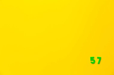 57 numaralı yeşil plastik oyuncak sarı arka planda, sağ alt köşede..