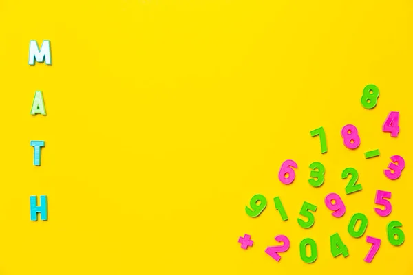 数学这个词用彩色塑料玩具字母写在黄色的背景上 近邻是数字从零到九的混乱顺序 笔记本或学校市场广告横幅墙纸 — 图库照片