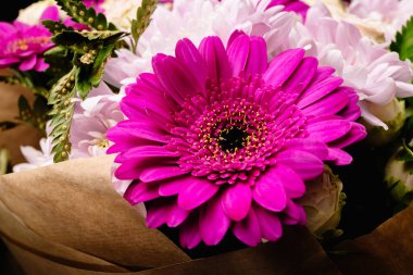 Büyük, güzel bir buket kasımpatı, gerberalar, pembe ve mor renkli eğrelti otları kahverengi el sanatları kağıdına sarılıp siyah bir arkaplanda izole edilmiş. Tatil için kartpostal. Yakın plan..