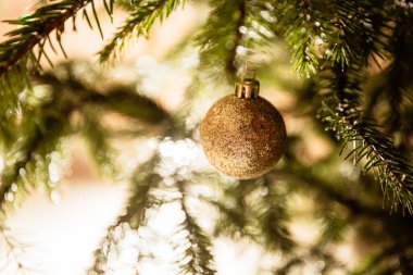 Mutlu Noeller ve mutlu yıllar. Ayna parçalarından yapılmış altın bir oyuncak top ve yemyeşil bir altın yay. Ev dekorasyonu, konforlu ortam ve kutlama havası ve büyülü ruh hali. Yakın plan..
