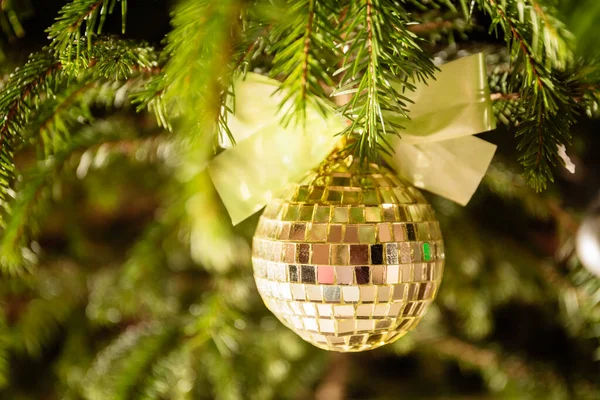 Merry Christmas and Happy New Year. A yellow toy ball made of pieces of a mirror with a lush golden bow. Home decoration and giving coziness and atmosphere of celebration and magical mood. Close-up.