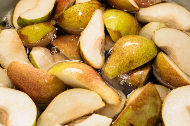 Bir çeyrekte dilimlenmiş tatlı armutlar turtaya ya da reçel şeklinde konserveye hazırlanmak için şekerle pişirilir. Kendi meyve suyunu yakın plan dilimler..