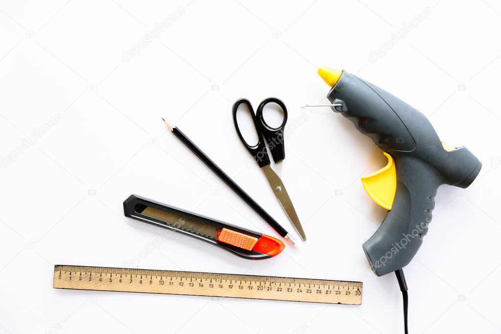 Ruler, knife, scissors, pencil and glue gun isolated on a white background. Tools for creating creative crafts. Stationery that can be used by adults or under their supervision. Top view layout