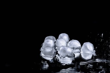 Eriyen buz küpleri, arka planda karanlık bir çekime karşı ayna yüzeyine yansıtılır. Soğuk içecekler için soğuk parçalar. Barı boyamak için..