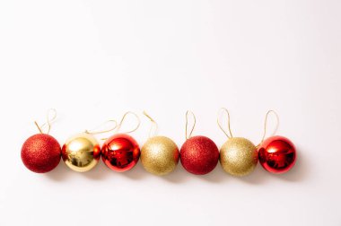 Beyaz arka planda izole edilmiş Noel ağacı oyuncakları. Yeni yıl parıltılı topları kırmızı ve altın renkleri düzenli olarak bulunur. Moda tarzında yazılar yazan şenlikli bir pankart. Yakın plan..
