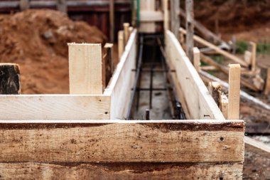 Beton dökmek ve bir bina ya da çit için sağlam bir temel oluşturmak için metal takviyeli kereste işi. İnşaat süreci.