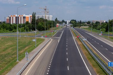 Yüksek binaların arka planına karşı otoyol ve şehrin girişinde bir inşaat vinci.