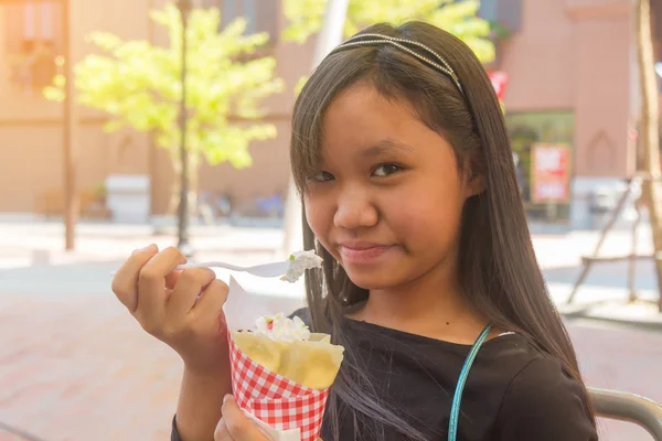 亚洲女孩吃绉甜甜点用勺子微笑在脸上 — 图库照片