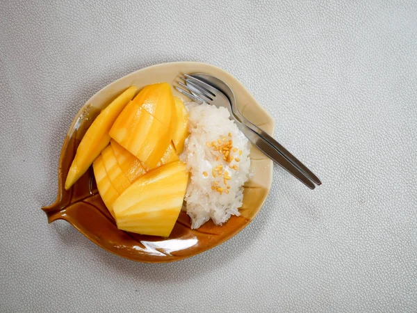 Mango yapışkan pirinç fasulye, yaprak şeklinde bir tabak içinde Hindistan cevizi krem ile tepesinde ile tepesinde.