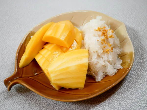 Mango yapışkan pirinç fasulye, yaprak şeklinde bir tabak içinde Hindistan cevizi krem ile tepesinde ile tepesinde.