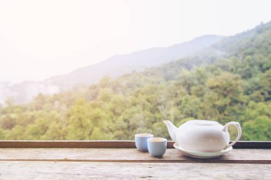 Çaydanlık ve çay bardağı sıcak veya sıcak kopya alan arka plan doğa ile ahşap masa üzerinde.