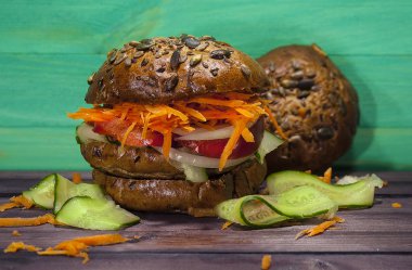 Ahşap bir masa, sağlıklı gıda sebze vejetaryen Burger. Lezzetli bir yemek için o kim kilo. Burger havuç ve salatalık