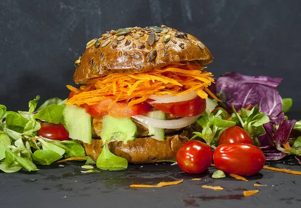 Vegetable vegetarian Burger on a wooden table, healthy food. A delicious lunch for those who lose weight. Burger with carrots and cucumber