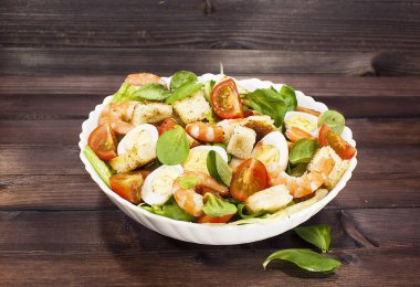 Karides salatası salata, roka, bıldırcın yumurtası, cherry domates, zeytin yağı ve ahşap bir masa üzerinde balsamik sirke ile. Sezar salata karides ile