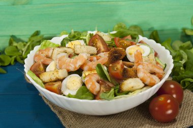Karides salatası marul, roka, Bıldırcın yumurta, domates, zeytin yağı ahşap bir masa üzerinde. Sezar salata karides ile