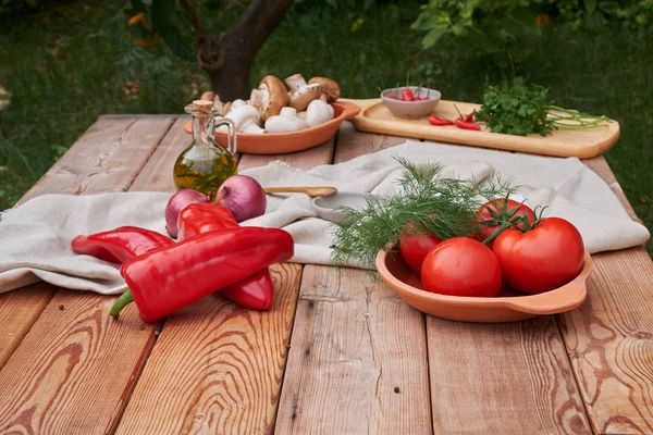 bir kil tabak, taze yeşillik, champignon mantar ve bir seramik tabak biber domates