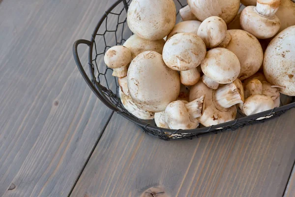Ahşap arka plan üzerinde bir sepet içinde champignon mantar
