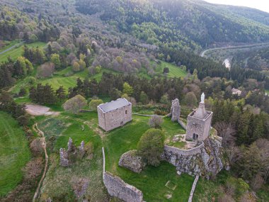 Tarihi Luc kalesi ve şapel kalıntıları ve tepedeki heykel manzarası, arka planda yeşil bir vadi ve orman, Lozere bölgesinin güzelliğini gözler önüne seriyor.