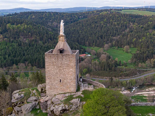 Luc Kalesi 'nin taş kulesi. Fransa' nın Lozere bölgesindeki yemyeşil vadi, orman ve dolambaçlı yola bakıyor.