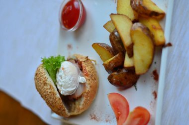 burger ve haşlanmış yumurta soslu dilimlenmiş patates kızartması