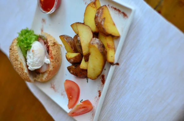 fried potatoes sliced with burger and poached egg with sauce