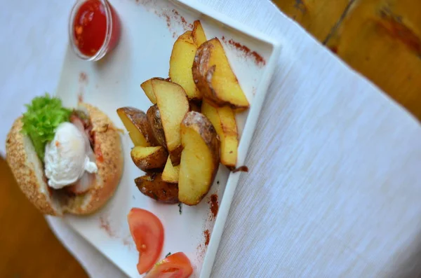 fried potatoes sliced with burger and poached egg with sauce