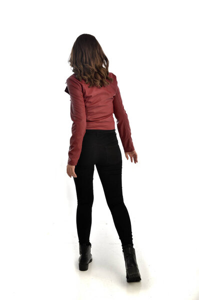 full length portrait of brunette girl wearing red leather jacket, black jeans and boots. standing pose, isolated on white studio background.