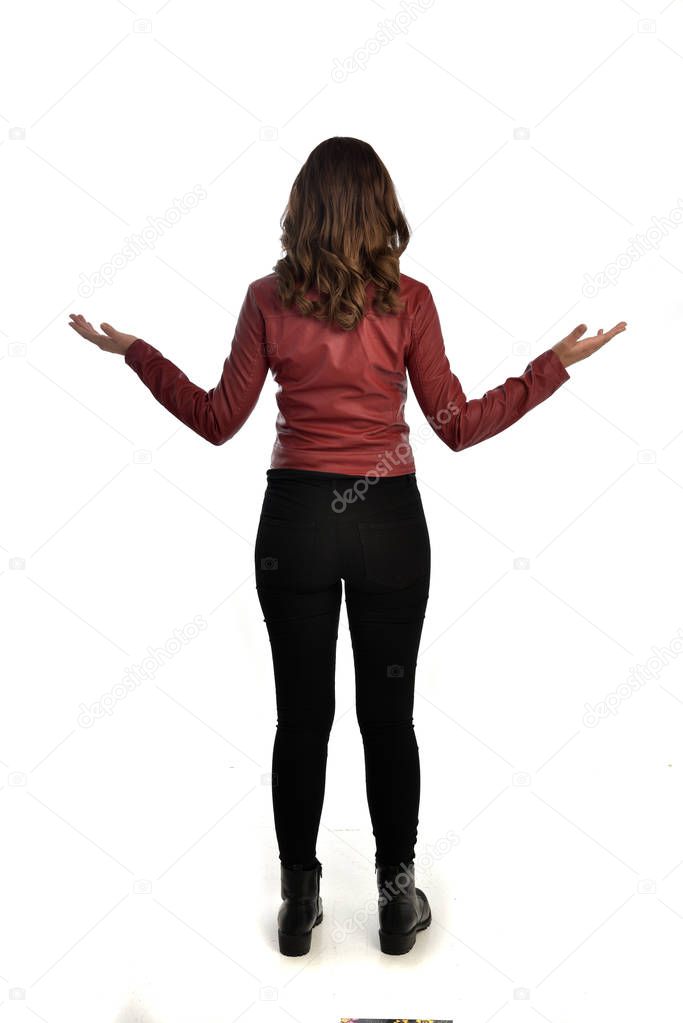 full length portrait of brunette girl wearing red leather jacket, black jeans and boots. standing pose, isolated on white studio background.