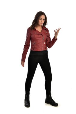 tam uzunlukta kırmızı deri ceket, siyah kot pantolon ve bot giyen esmer kız portresi. ayakta poz, beyaz stüdyo arka plan üzerinde izole.