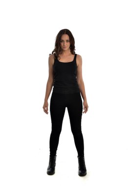 Tam boy siyah singlet, kot kot pantolon ve bot giyen esmer kız portresi. ayakta poz, beyaz stüdyo arka plan üzerinde izole.