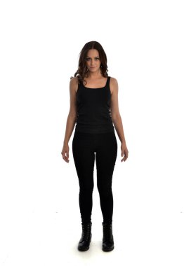 Tam boy siyah singlet, kot kot pantolon ve bot giyen esmer kız portresi. ayakta poz, beyaz stüdyo arka plan üzerinde izole.