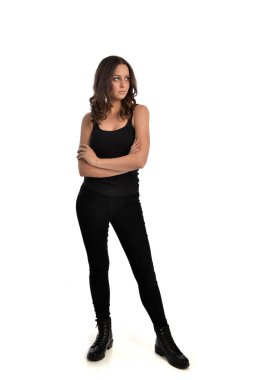 Tam boy siyah singlet, kot kot pantolon ve bot giyen esmer kız portresi. ayakta poz, beyaz stüdyo arka plan üzerinde izole.