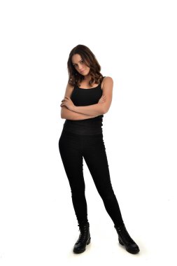 Tam boy siyah singlet, kot kot pantolon ve bot giyen esmer kız portresi. ayakta poz, beyaz stüdyo arka plan üzerinde izole.