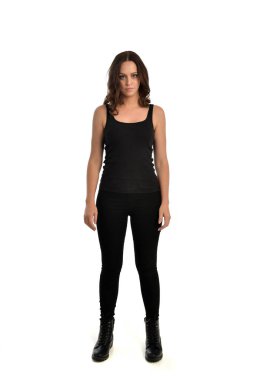 Tam boy siyah singlet, kot kot pantolon ve bot giyen esmer kız portresi. ayakta poz, beyaz stüdyo arka plan üzerinde izole.