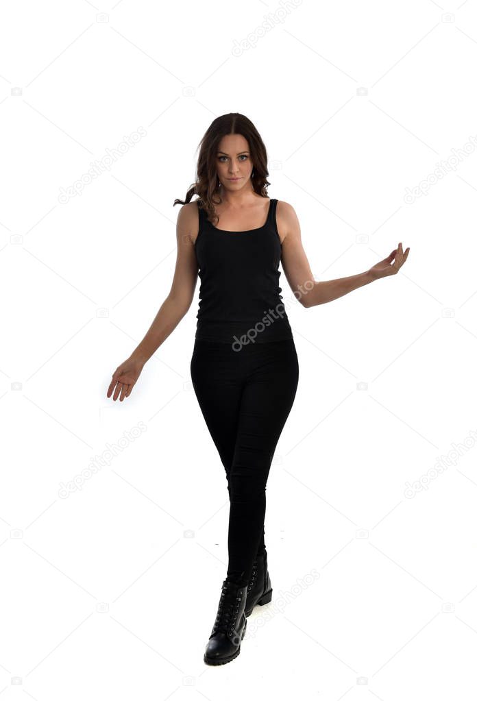 full length portrait of brunette girl wearing black singlet, jeans jeans and boots. standing pose, isolated on white studio background.