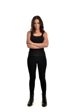 Tam boy siyah singlet, kot kot pantolon ve bot giyen esmer kız portresi. ayakta poz, beyaz stüdyo arka plan üzerinde izole.