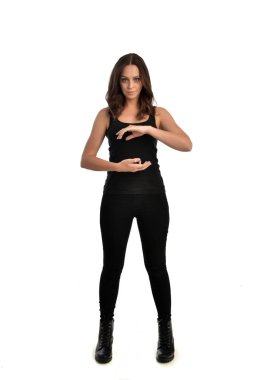 Tam boy siyah singlet, kot kot pantolon ve bot giyen esmer kız portresi. ayakta poz, beyaz stüdyo arka plan üzerinde izole.