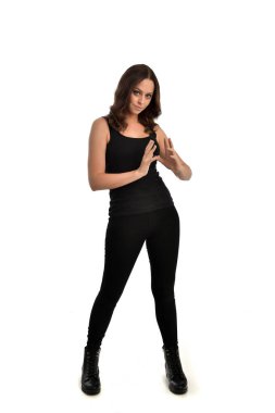 Tam boy siyah singlet, kot kot pantolon ve bot giyen esmer kız portresi. ayakta poz, beyaz stüdyo arka plan üzerinde izole.