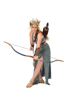 tam uzunlukta fantezi toga elbisesi giymiş ve ok ve yay tutan güzel sarışın Bayan portresi. Beyaz arka plan üzerinde ayakta poz.