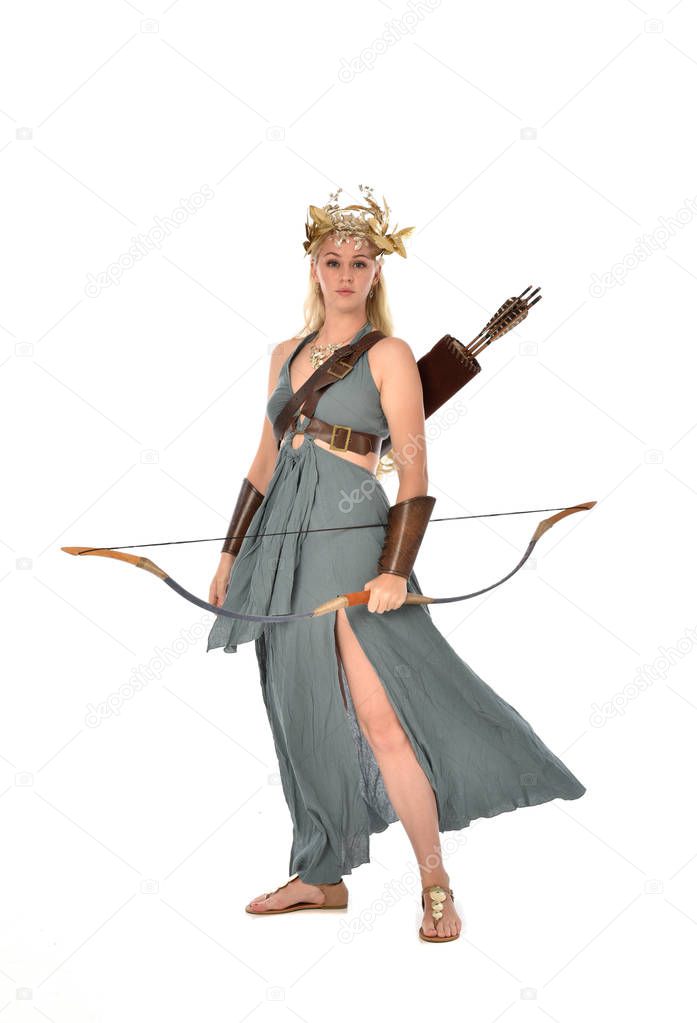 full length portrait of pretty blonde lady wearing fantasy toga gown,  and holding a bow and arrow. standing pose on white background.