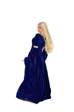 tam uzunlukta bir mavi fantezi Ortaçağ elbisesi giymiş güzel sarışın kadın portresi. ayakta poz fotoğraf makinesi beyaz stüdyo arka plan üzerinde uzak karşı karşıya.