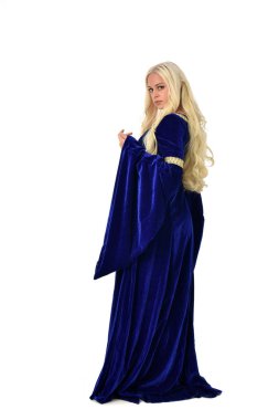 tam uzunlukta bir mavi fantezi Ortaçağ elbisesi giymiş güzel sarışın kadın portresi. ayakta poz fotoğraf makinesi beyaz stüdyo arka plan üzerinde uzak karşı karşıya.