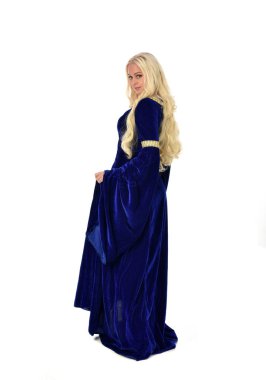 tam uzunlukta bir mavi fantezi Ortaçağ elbisesi giymiş güzel sarışın kadın portresi. ayakta poz fotoğraf makinesi beyaz stüdyo arka plan üzerinde uzak karşı karşıya.